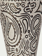 Close-up of paisley pattern on a cream cone cup with dark ornamental linework