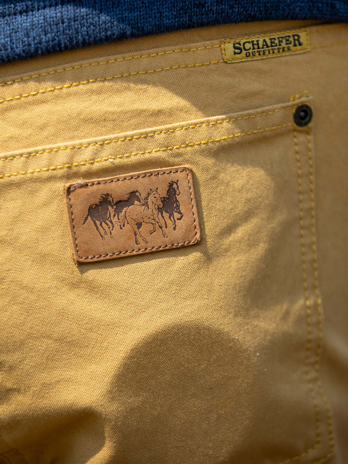 Tan canvas dungaree pants back pocket with leather patch and horse logo