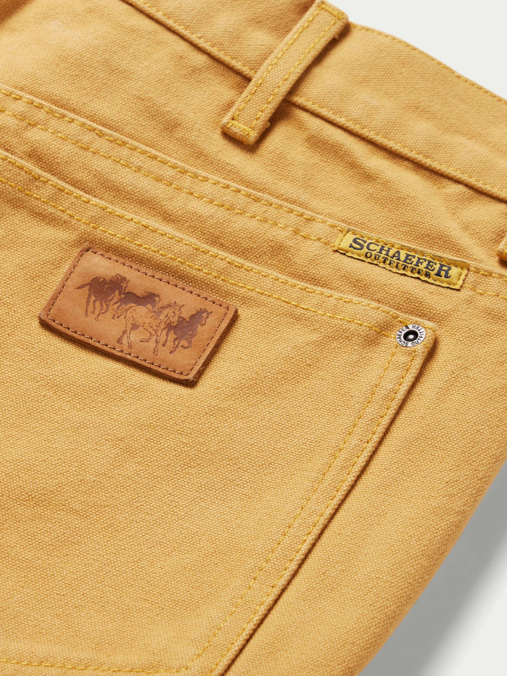 Tan canvas dungaree pants front pocket with leather brand patch and snap button