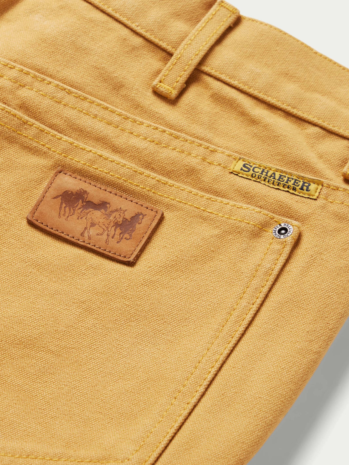 Tan canvas dungaree pants front pocket with leather brand patch and snap button