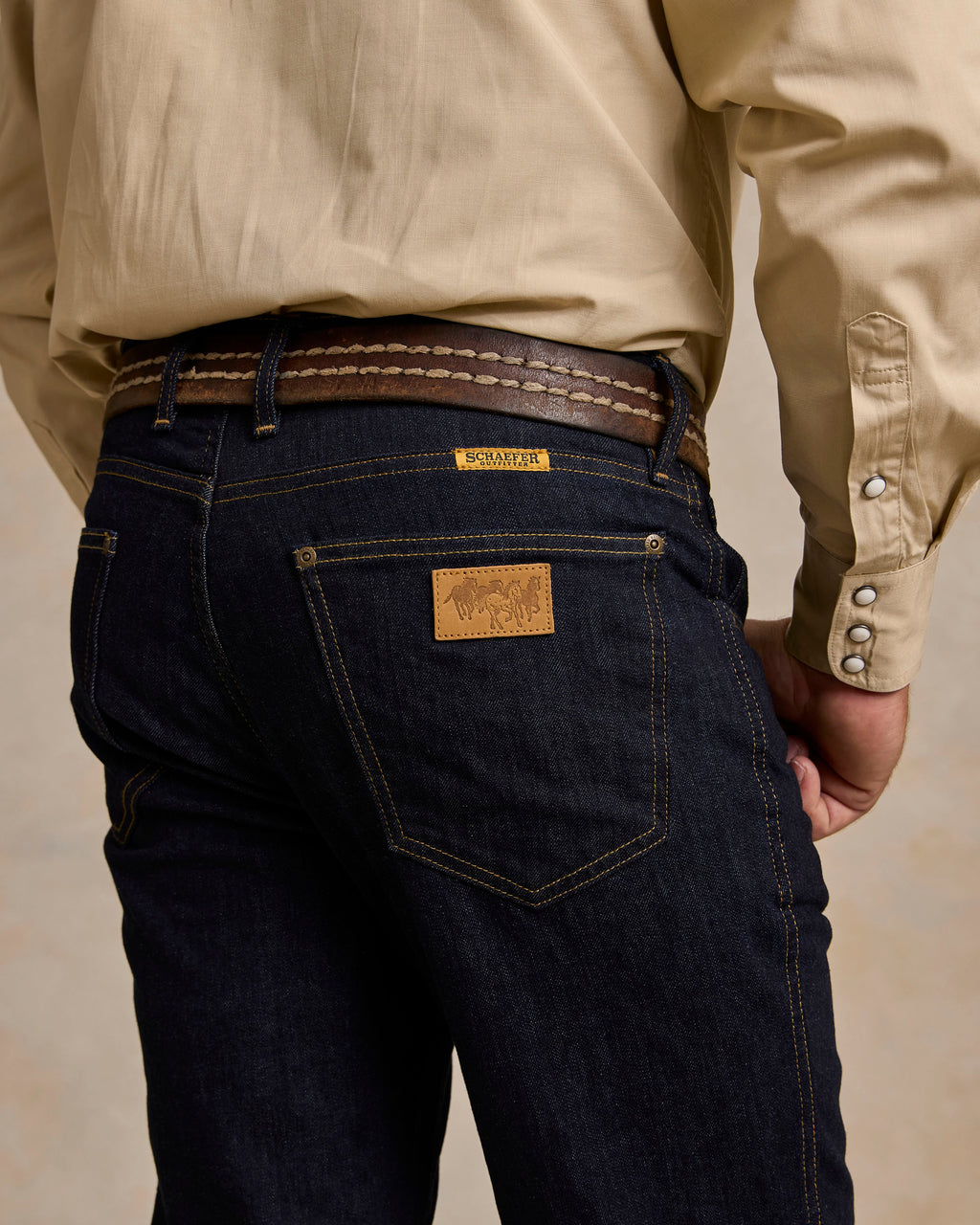 Dark rinse jeans back pocket close-up with leather patch and yoke stitching