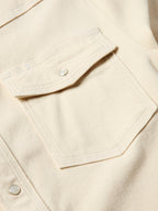 Natural denim snap shirt chest pocket detail with metal snap button and contrast stitching