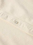 Natural denim shirt seam and round metal snap detail close-up