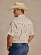 Short-sleeve pearl snap shirt on model, back view: white with small blue floral pattern.