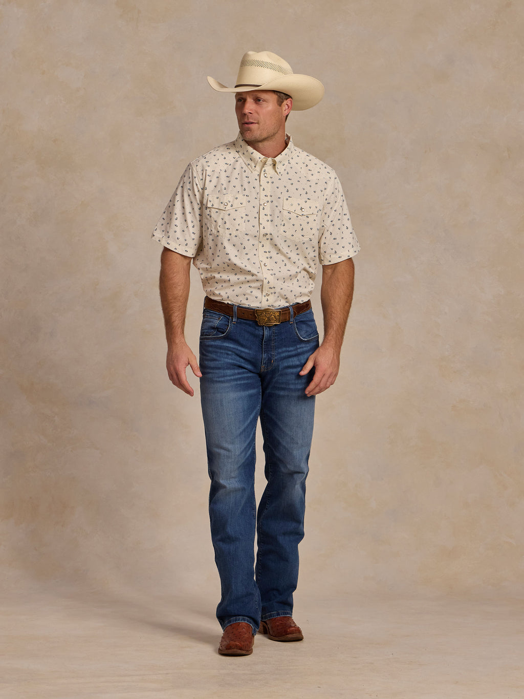 Short-sleeve pearl snap shirt on model: white with small blue floral pattern, chest pocket.