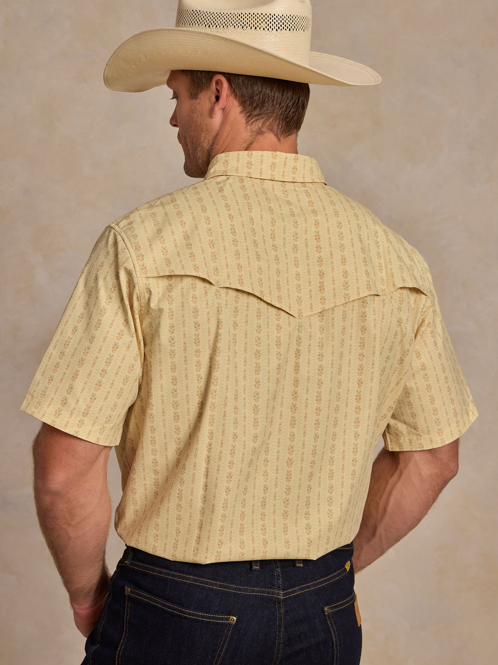 Short sleeve pearl snap western shirt, back view; light cream patterned with stitched yoke.