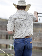 Short-sleeve pearl snap shirt on model, back view: white with small blue floral pattern.