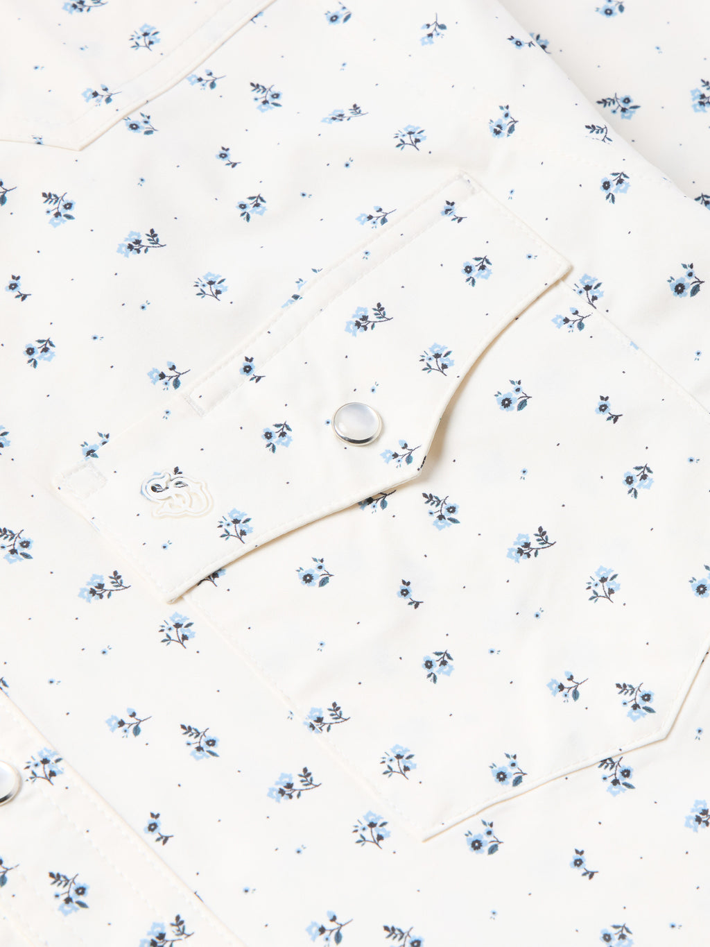 Short-sleeve pearl snap shirt detail: white fabric, blue floral print, round snap buttons.