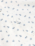 Short-sleeve pearl snap shirt fabric detail in white with small blue floral print and snap.