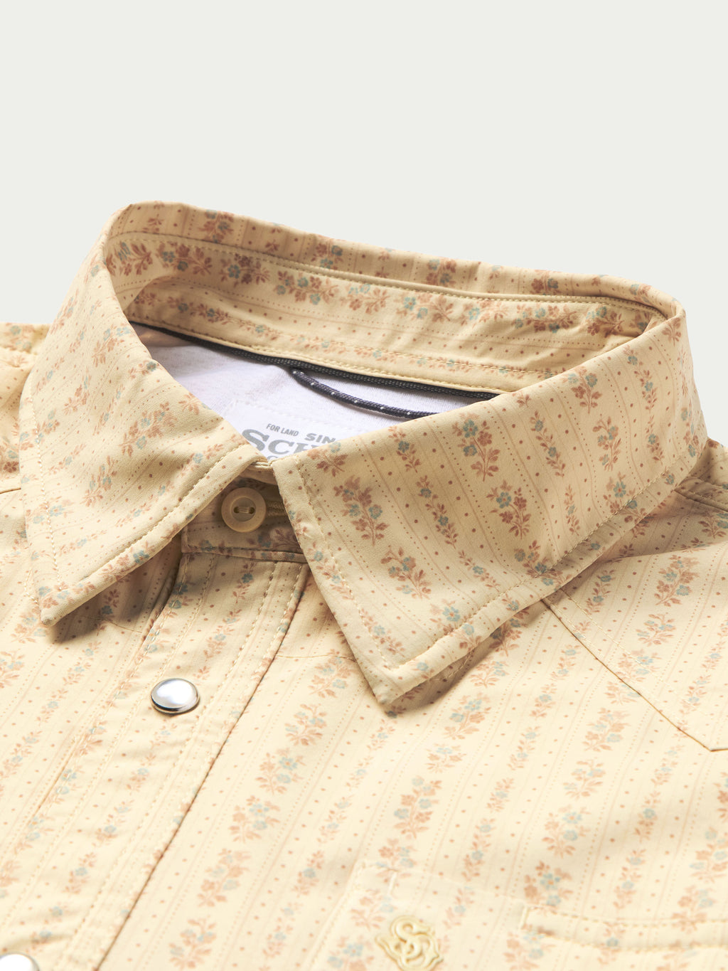 Short sleeve western shirt with pearl snap placket and pointed yoke; cream patterned.