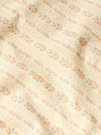 Close-up of light cream western shirt fabric with small floral print and stitched lines.