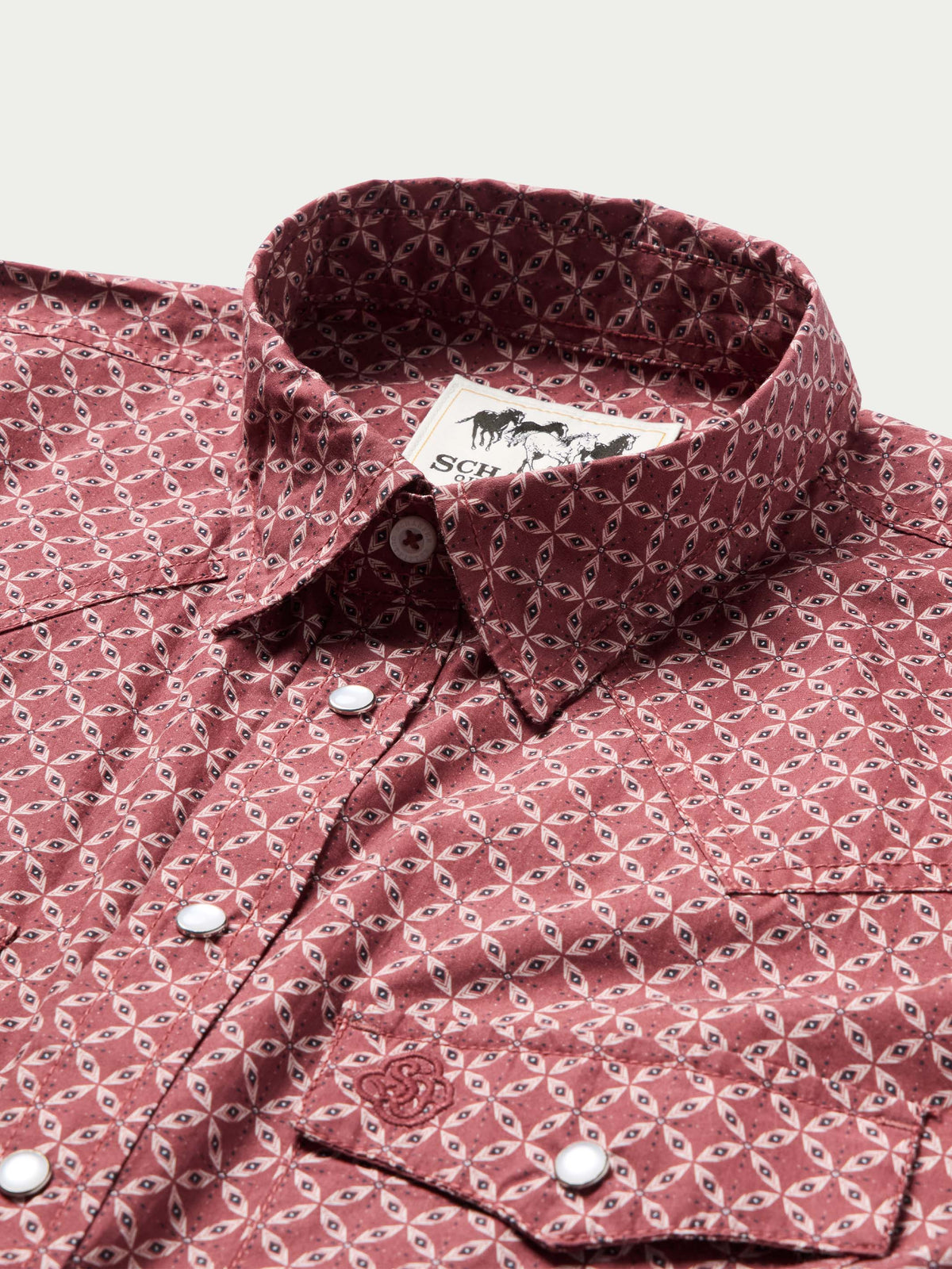Cotton snap shirt collar and button placket in dark red with repeating geometric pattern.