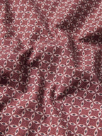 Dark red cotton snap shirt fabric with repeating small geometric pattern, close-up view.