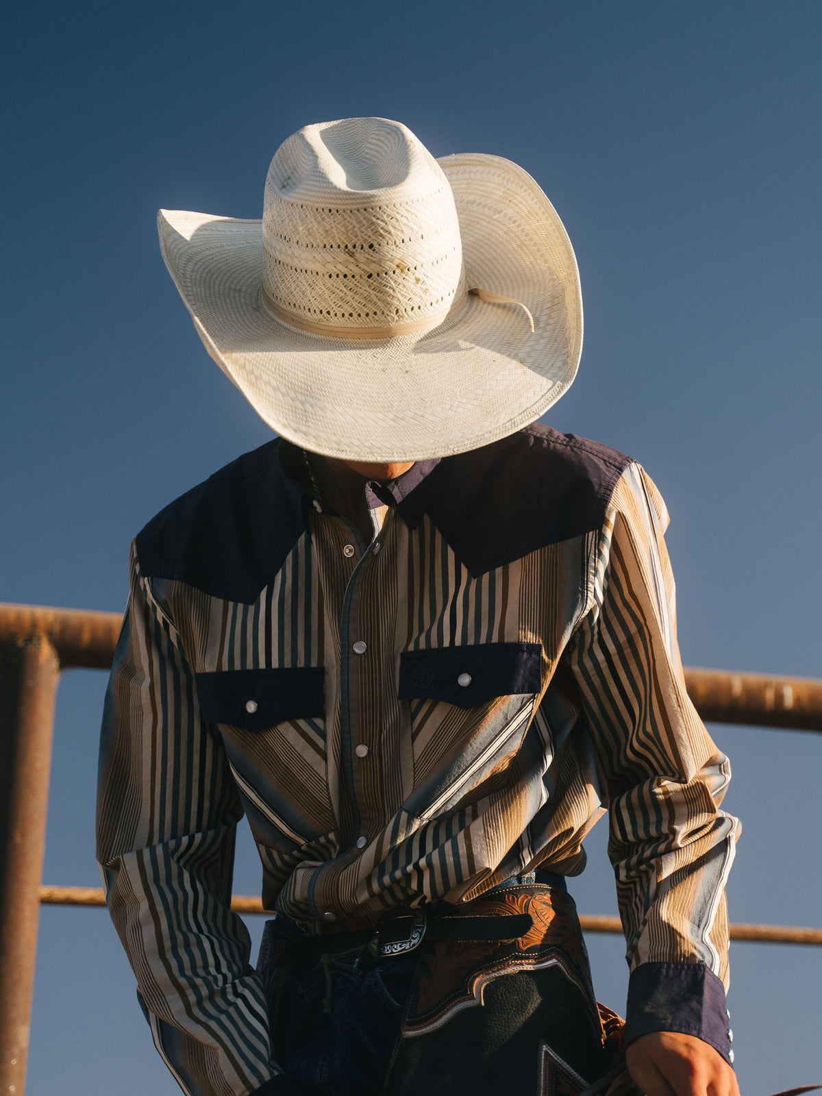 Cotton snap shirt worn by rider, navy collar and chest pockets on striped fabric