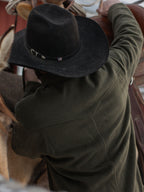 Olive wool overshirt with button front and chest pockets, worn with a dark hat.