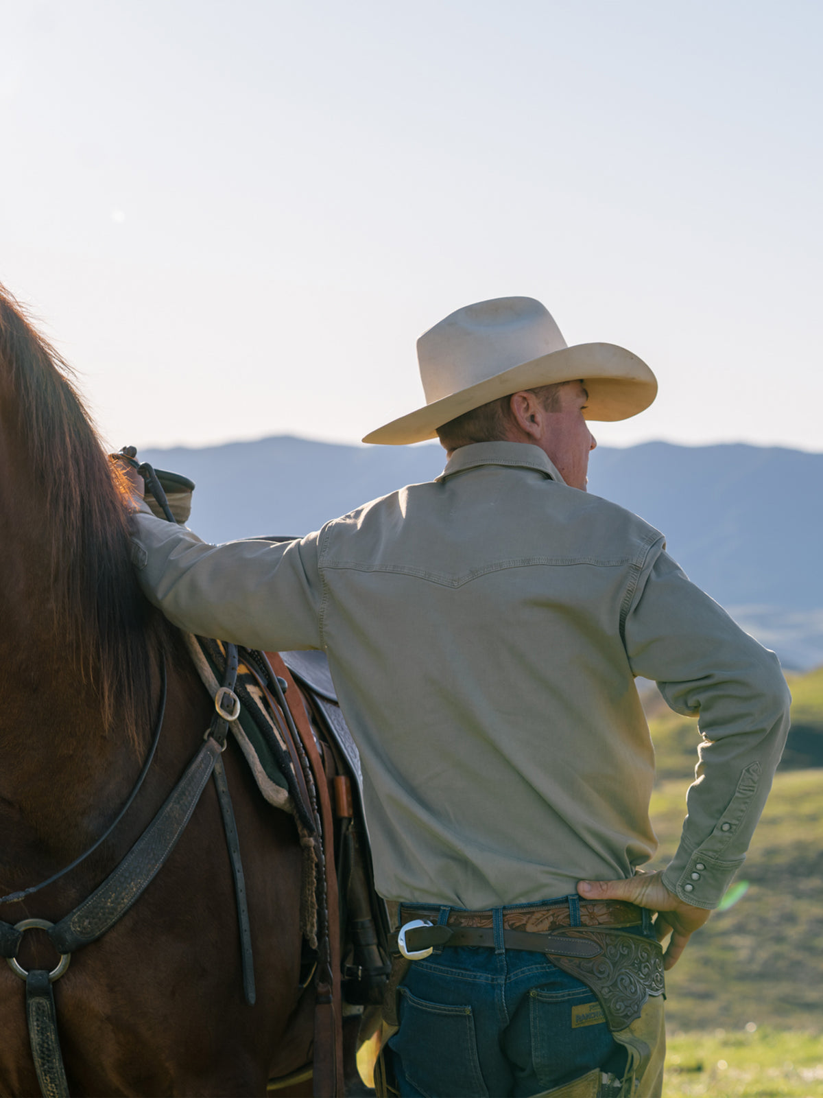 Sage western snap denim shirt worn from behind, long sleeves and yoke seam