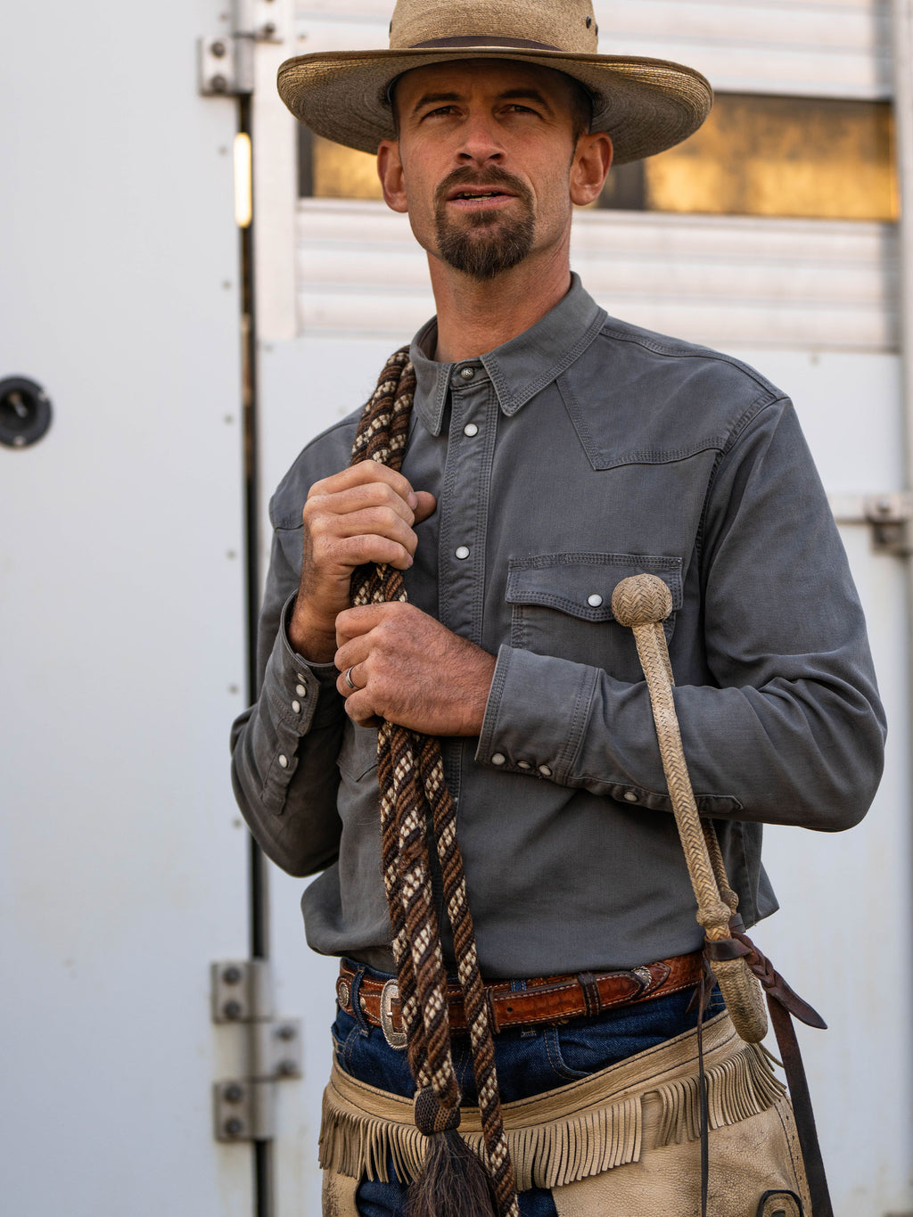 Men's western denim snap shirt in dark carbon gray on a cowboy, chest pockets visible.