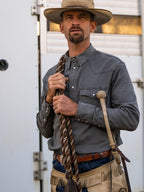 Men's western denim snap shirt in dark carbon gray on a cowboy, chest pockets visible.