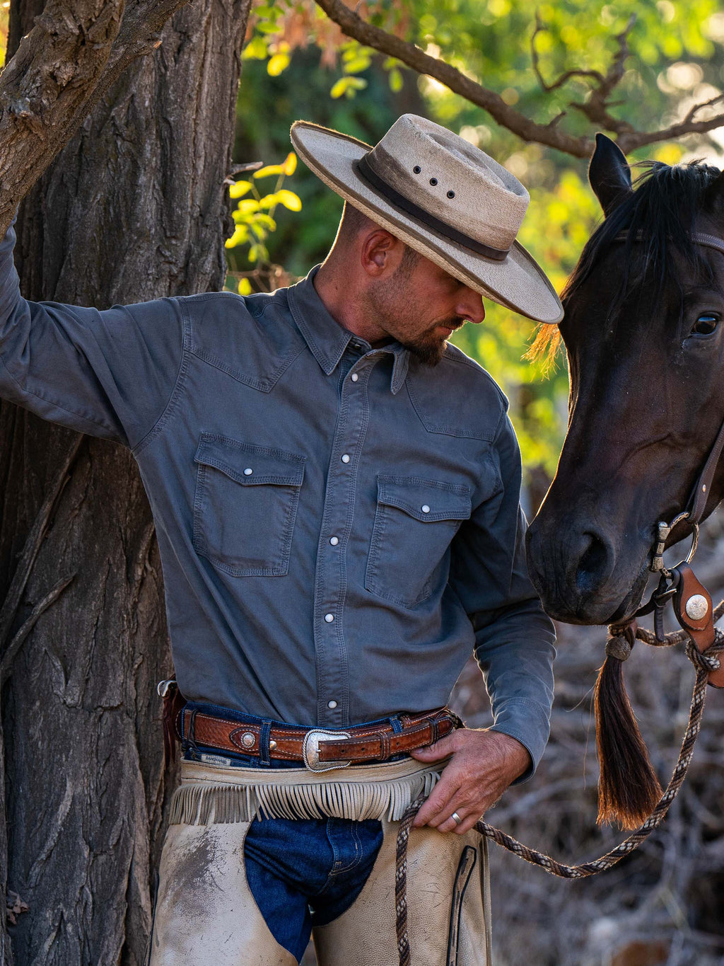 Men's western denim snap shirt in dark carbon gray worn by a cowboy, front in view.