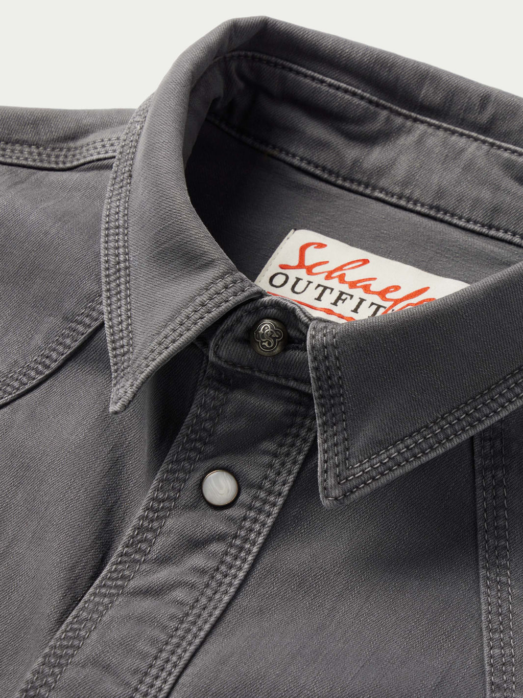 Men's western denim snap shirt collar detail with button-front placket and brand patch.