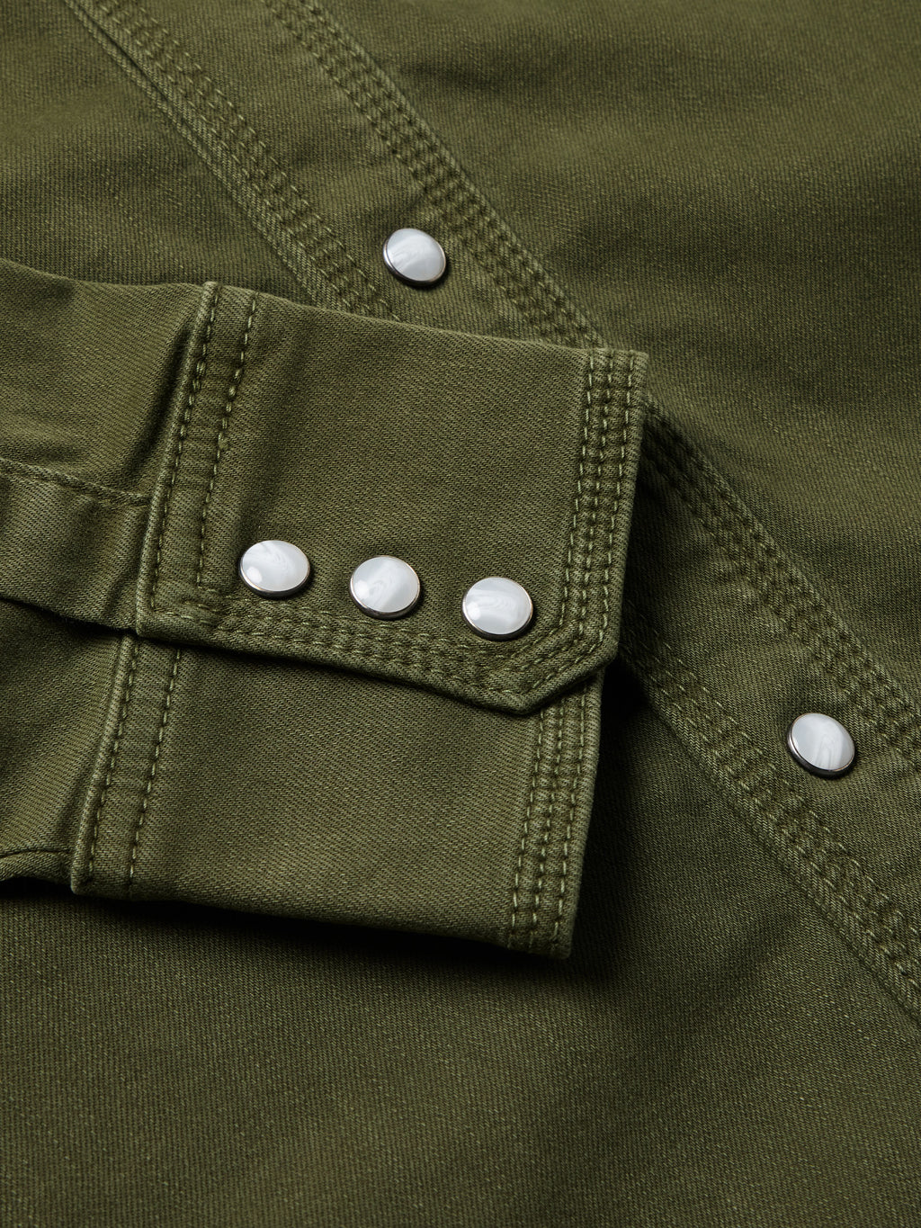 Dark olive denim snap shirt cuff with white snap buttons and pocket flap