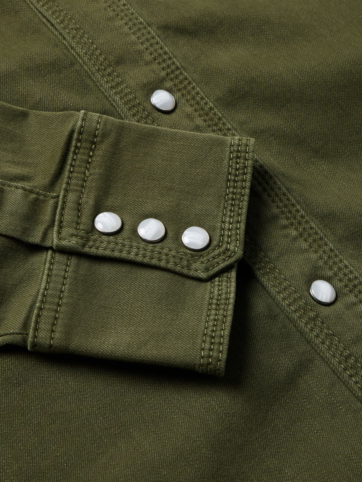 Dark olive denim snap shirt cuff with white snap buttons and pocket flap