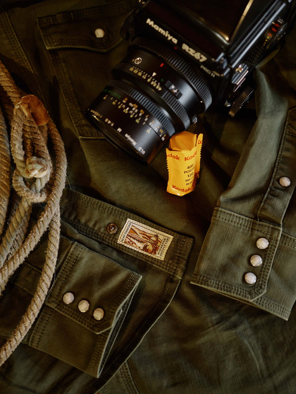 Dark olive denim snap shirt close-up with metal snaps and embroidered front pocket patch