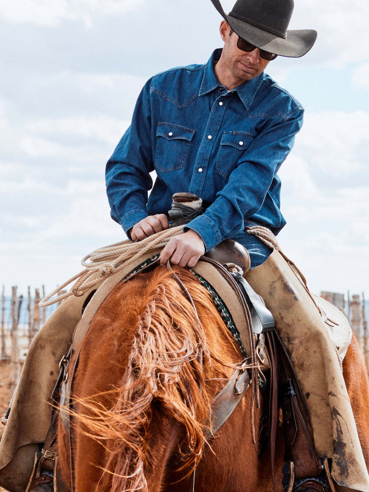 Dark indigo denim snap shirt worn by cowboy, snap front and collar visible