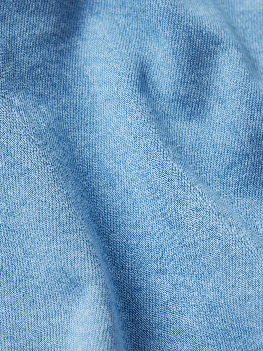 Light-wash denim snap shirt fabric close-up, textured blue weave