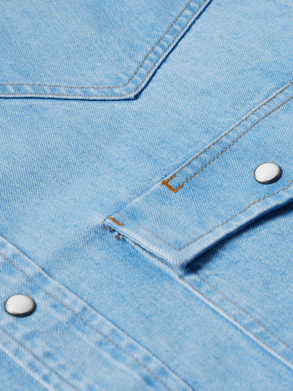 Light-wash denim snap shirt detail, stitched yoke seam and metal snap placket