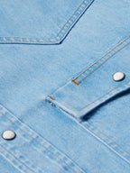 Light-wash denim snap shirt detail, stitched yoke seam and metal snap placket