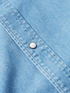 Light-wash denim snap shirt close-up, yoke seam with round metal snap