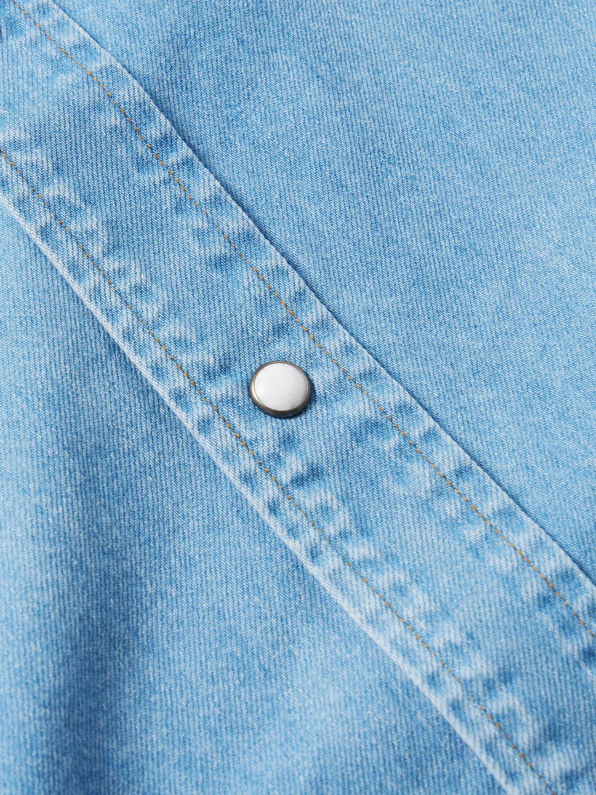 Light-wash denim snap shirt close-up, yoke seam with round metal snap