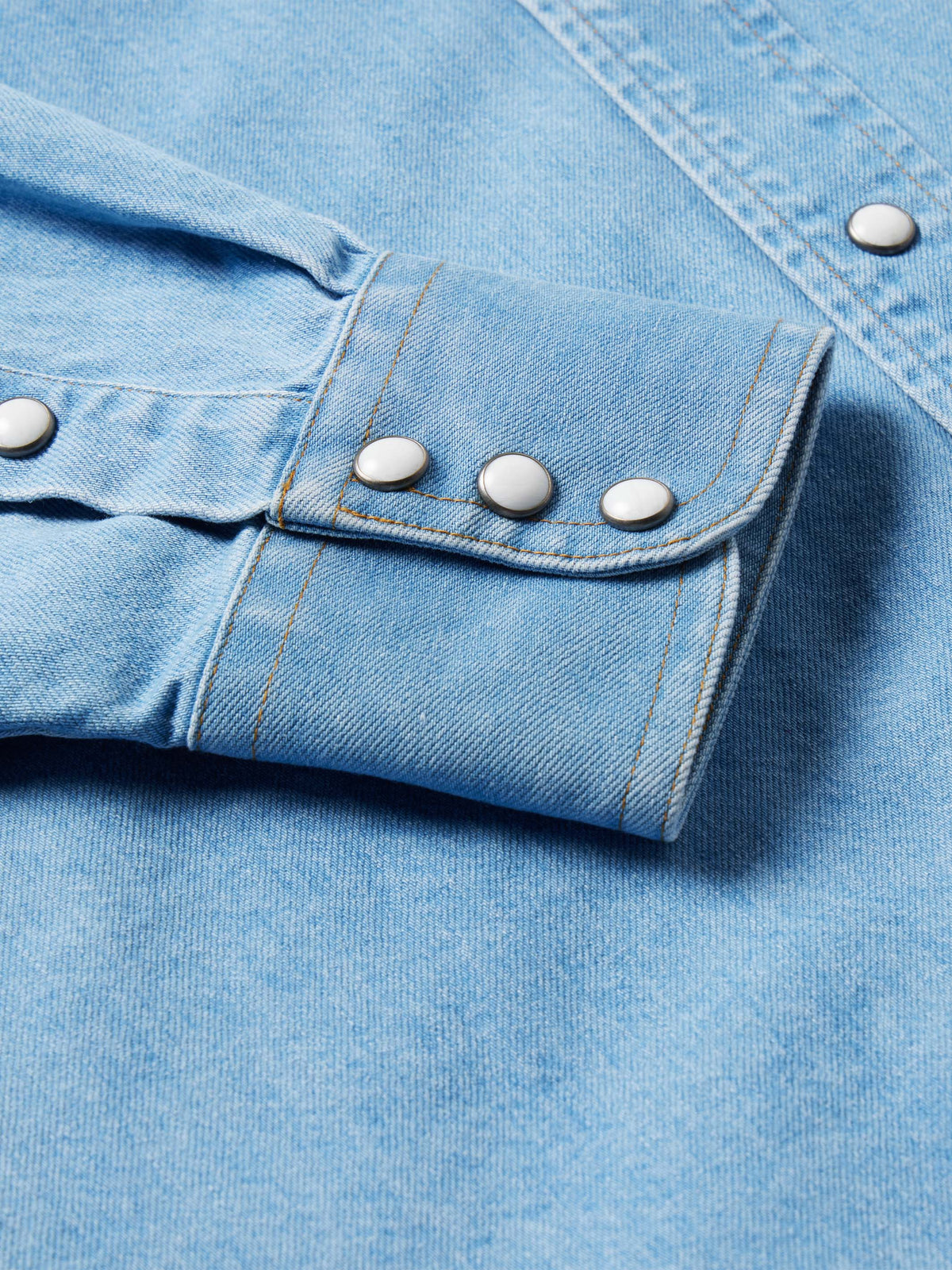 Light-wash denim snap shirt cuff detail, snap closure with reinforced stitching