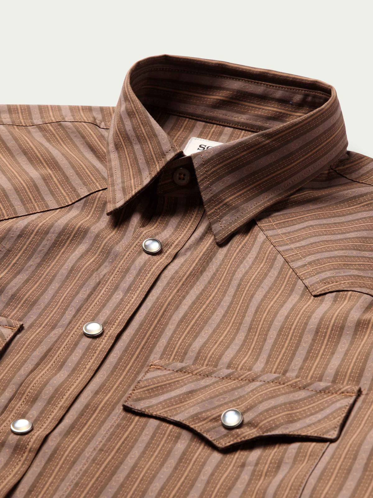 Close-up of western striped shirt placket with snap buttons and pointed collar