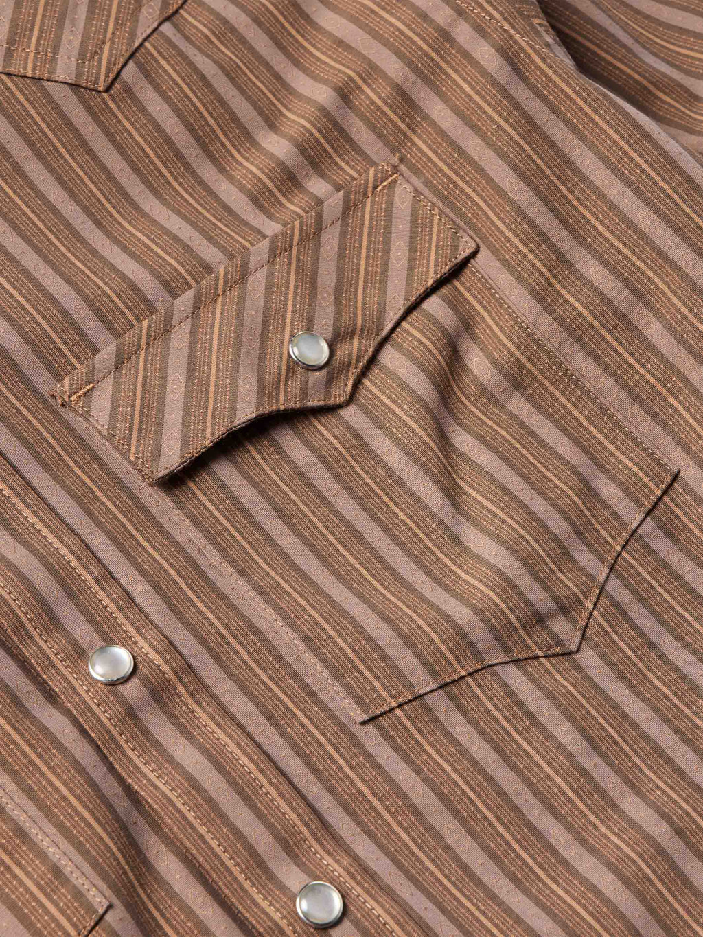 Close-up of western striped shirt chest pocket with snap flap and metal snap buttons