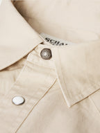 Light beige button-up shirt collar with snap and logo patch at neckline