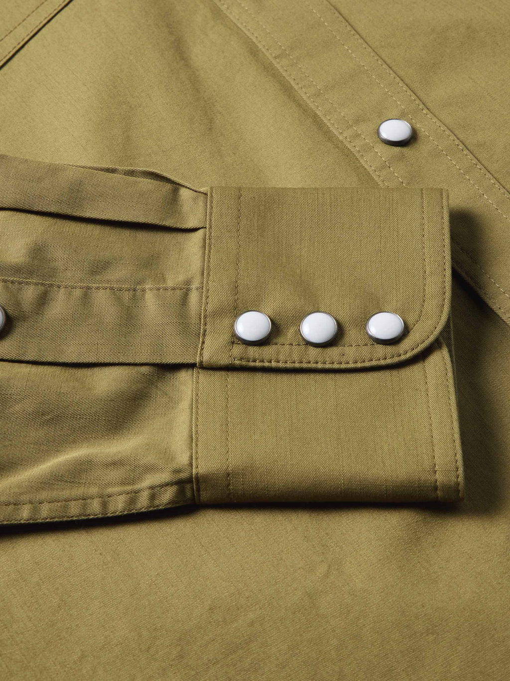 Olive slub twill shirt showing chest pocket flaps with white snap buttons