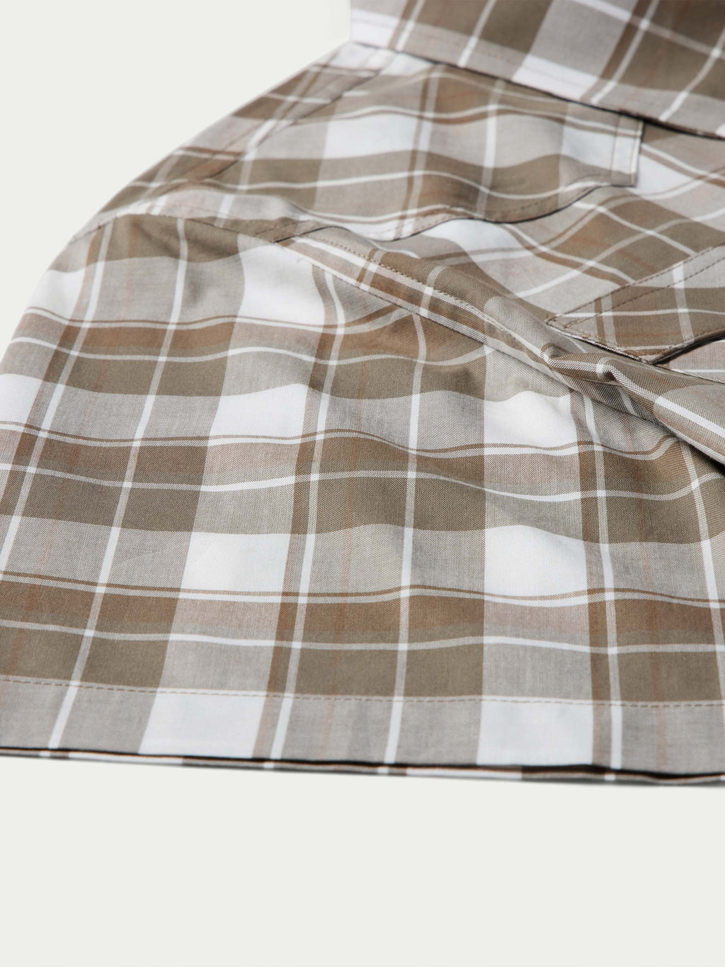 Tan and white plaid cotton fabric close-up with smooth drape folds