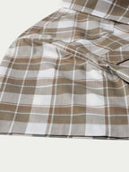 Tan and white plaid cotton fabric close-up with smooth drape folds