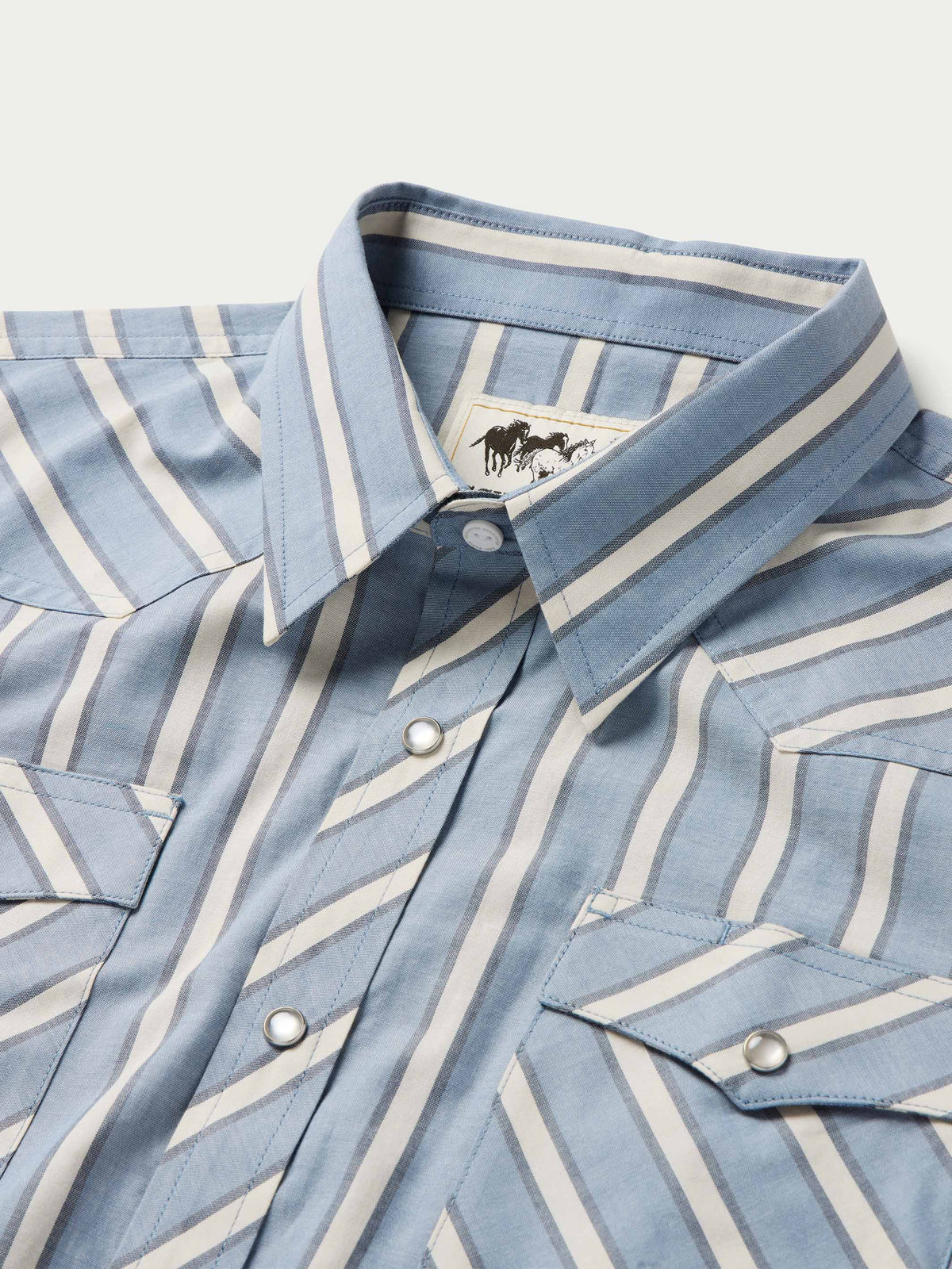 Collar and placket close-up of blue and white striped pearl snap button-up shirt