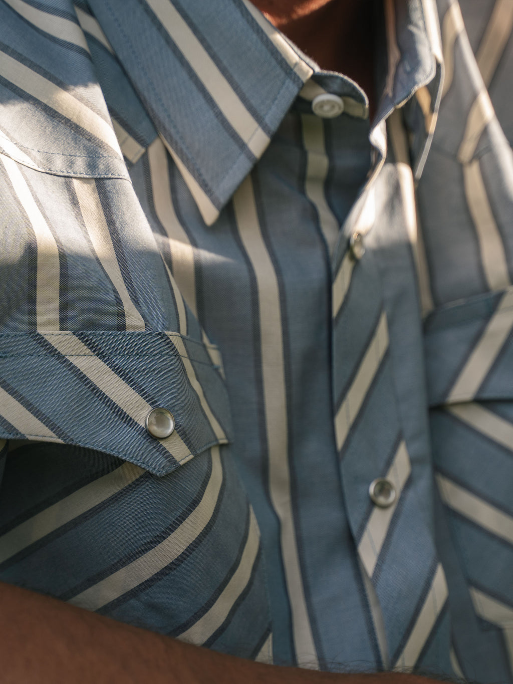 Close-up of blue and white striped western shirt with metal pearl snap buttons