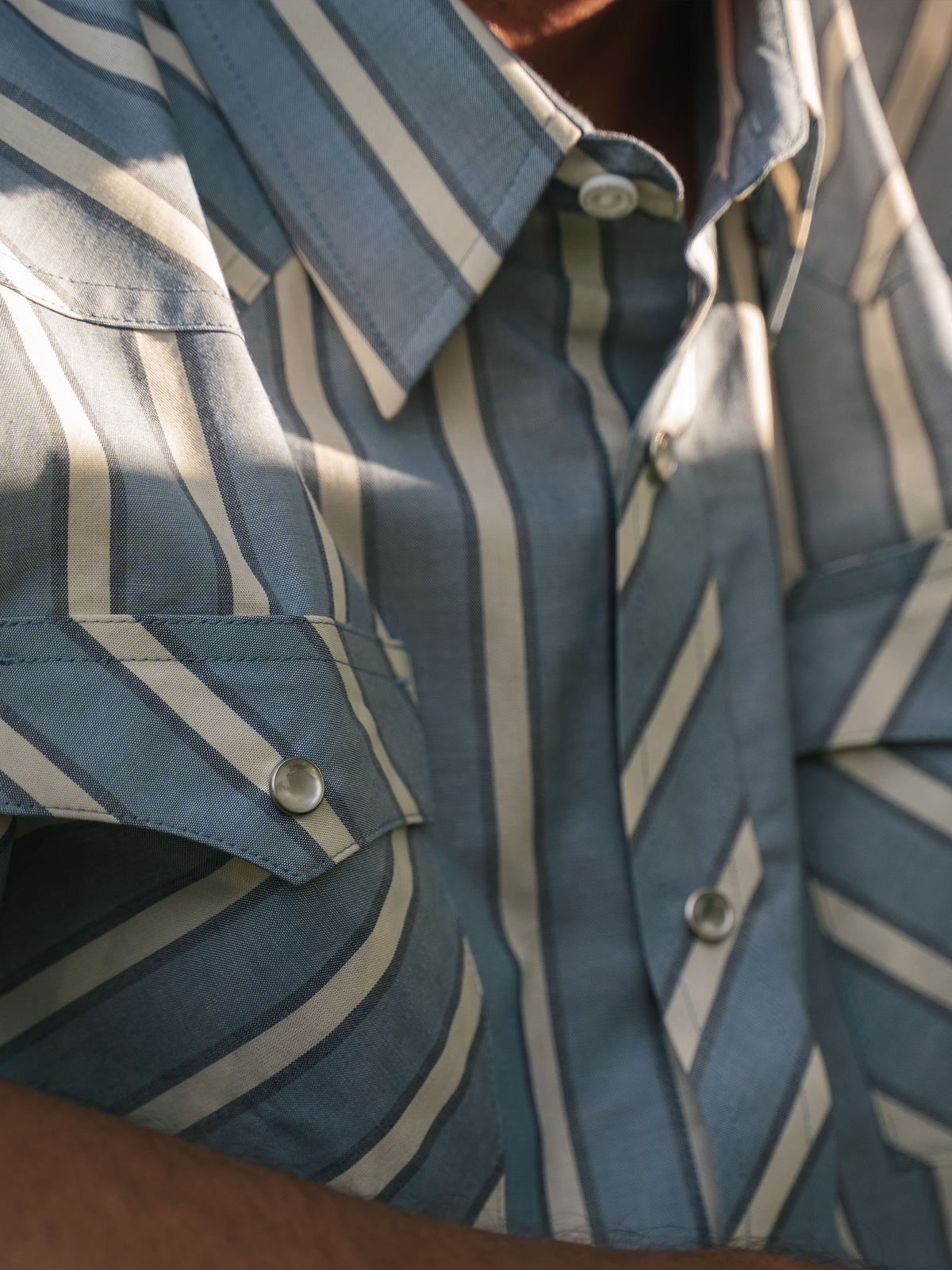Close-up of blue and white striped western shirt with metal pearl snap buttons