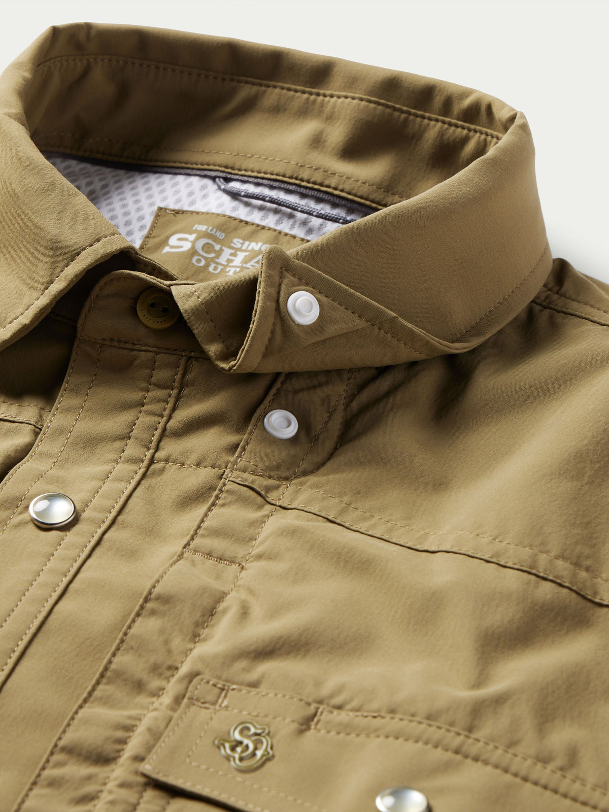 Olive snap shirt button placket close-up with chest pocket stitching