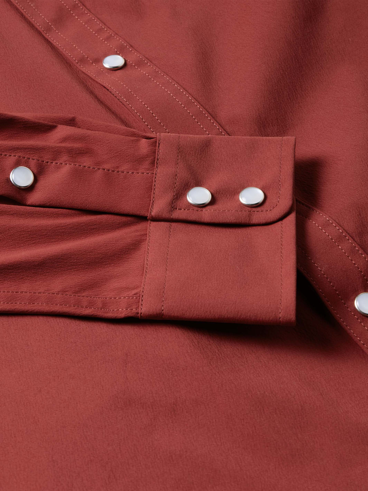 Oxblood snap cuff with metal buttons and stitched seams on the sleeve