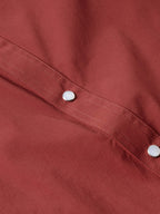 Oxblood western shirt yoke seam with metal snap buttons along the panel