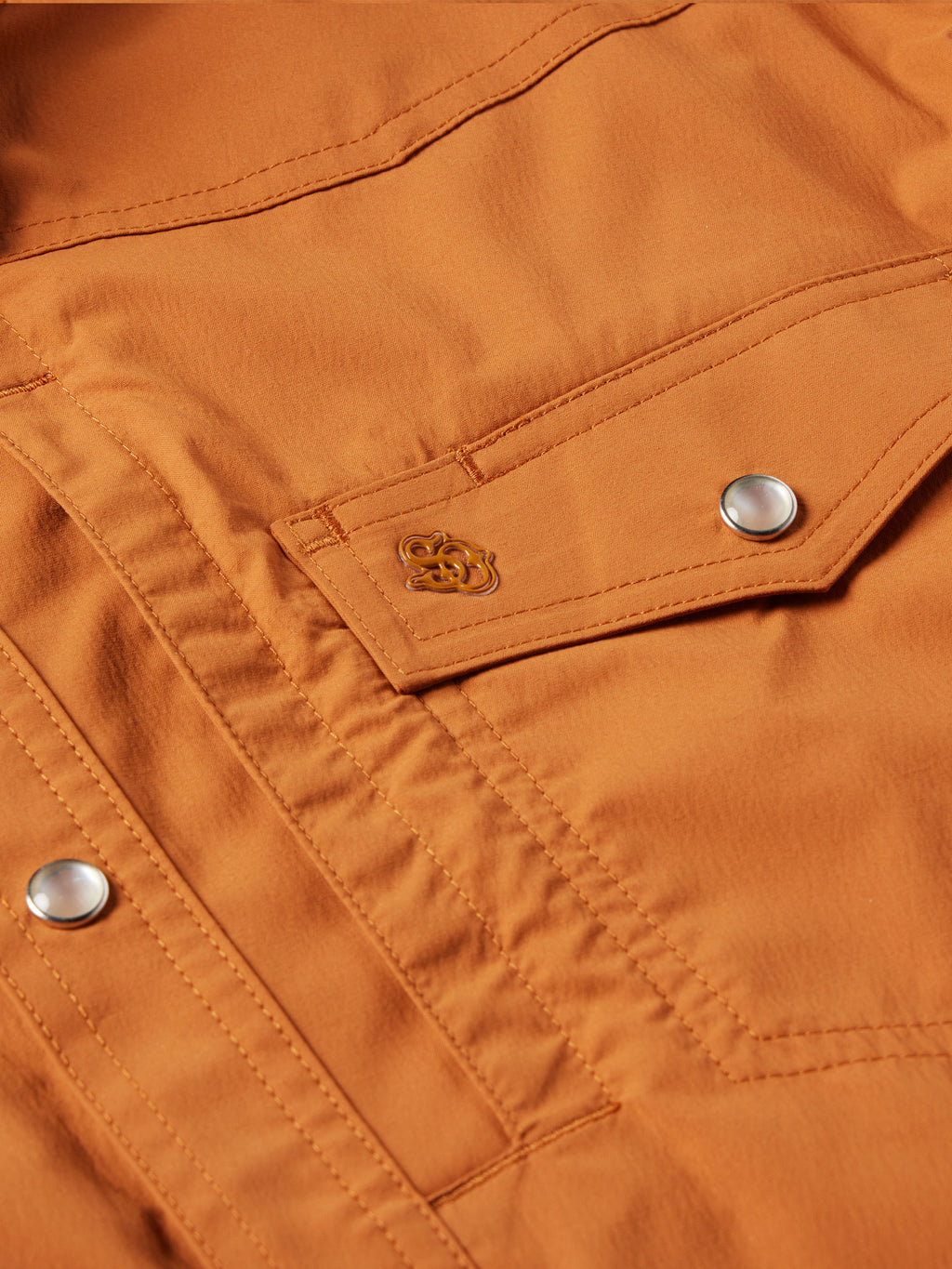 Rust snap shirt chest pocket flap with embroidered badge and snap button