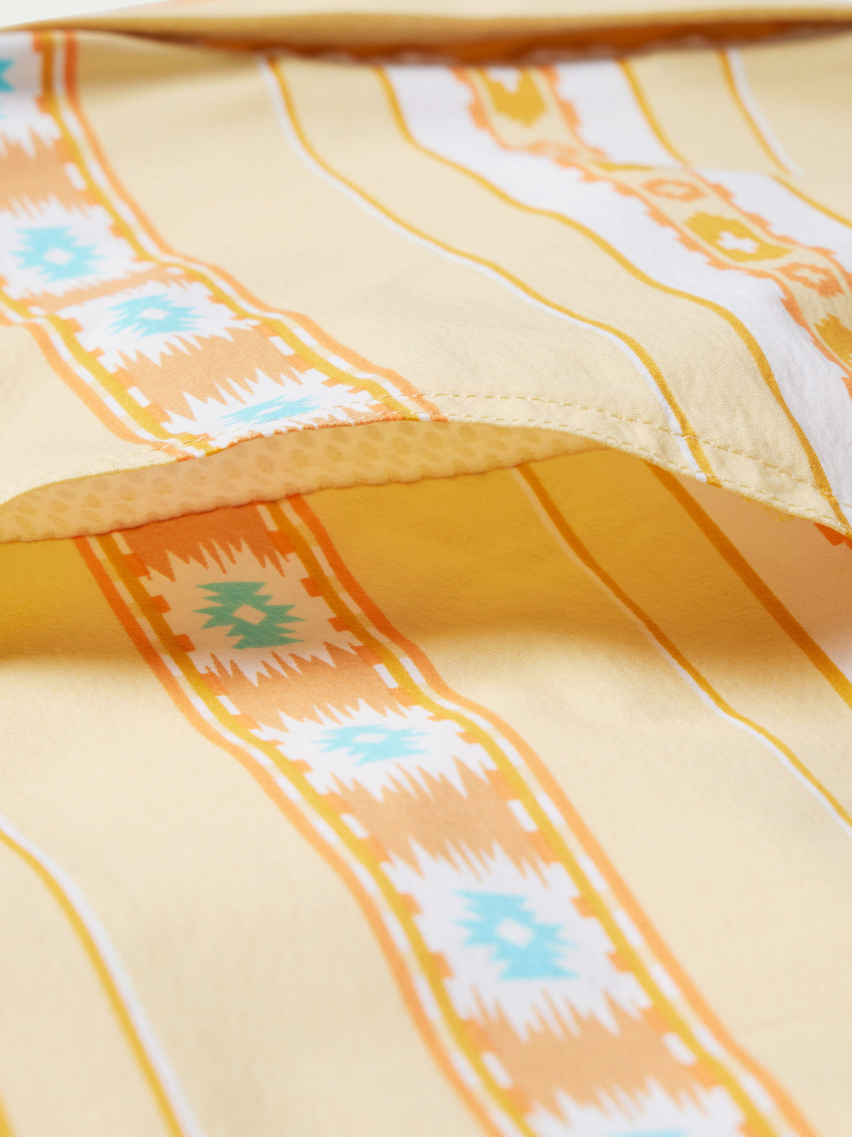 Western snap shirt fabric with cream base and orange, blue, and white Aztec stripes