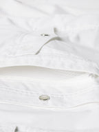 White shirt interior neckline and snap strap detail with metal snap button close-up
