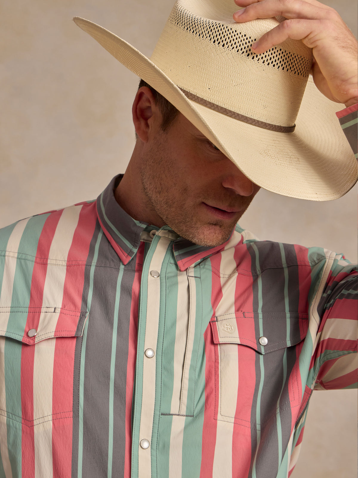 Western snap shirt with pointed yoke seam and vertical teal-pink-white stripes.
